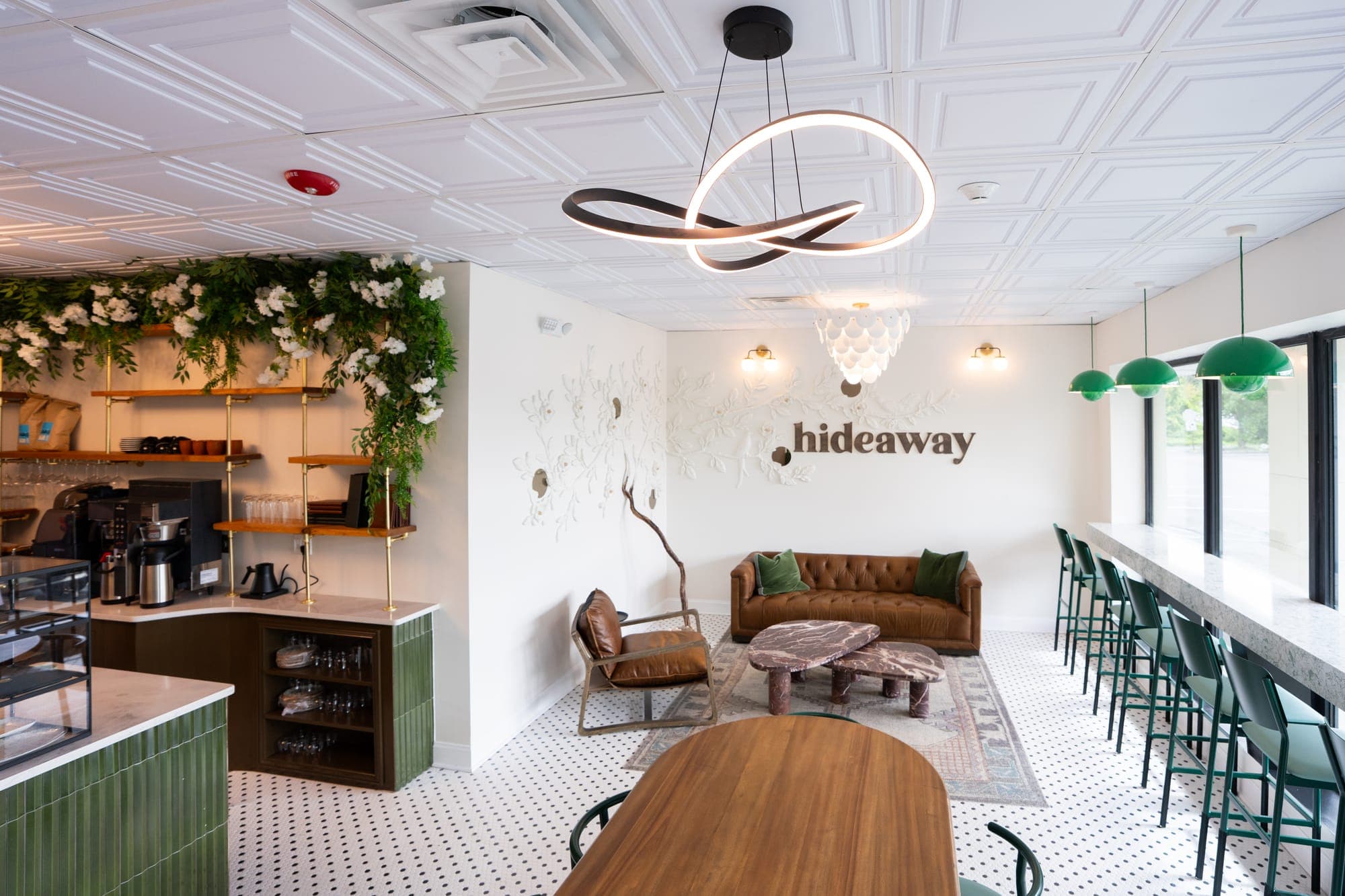 The long wooden table in the main room, with the sofa and the hideaway sign beyond