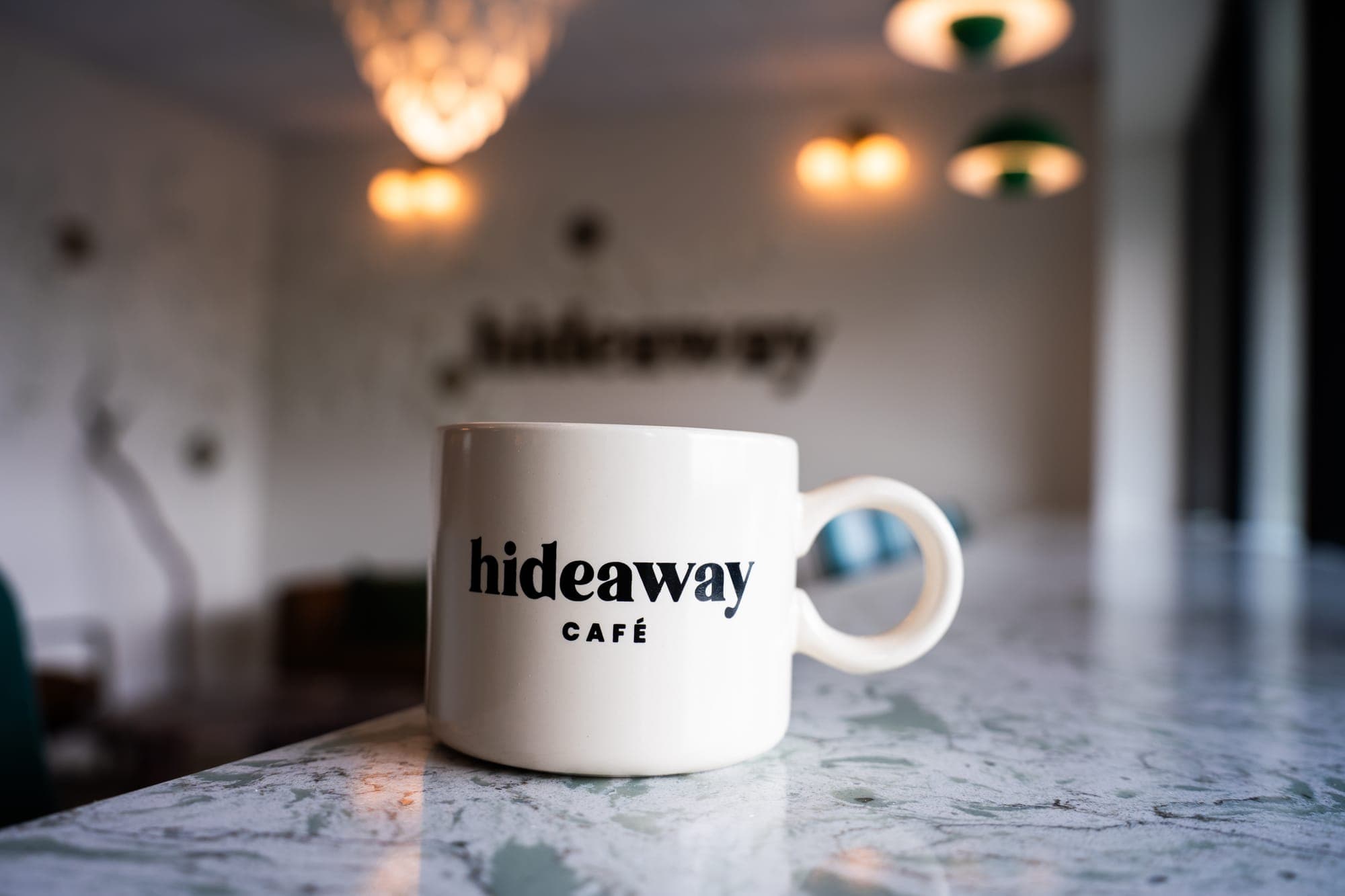 A hideaway cafe mug on the counter, the room softly lit behind it